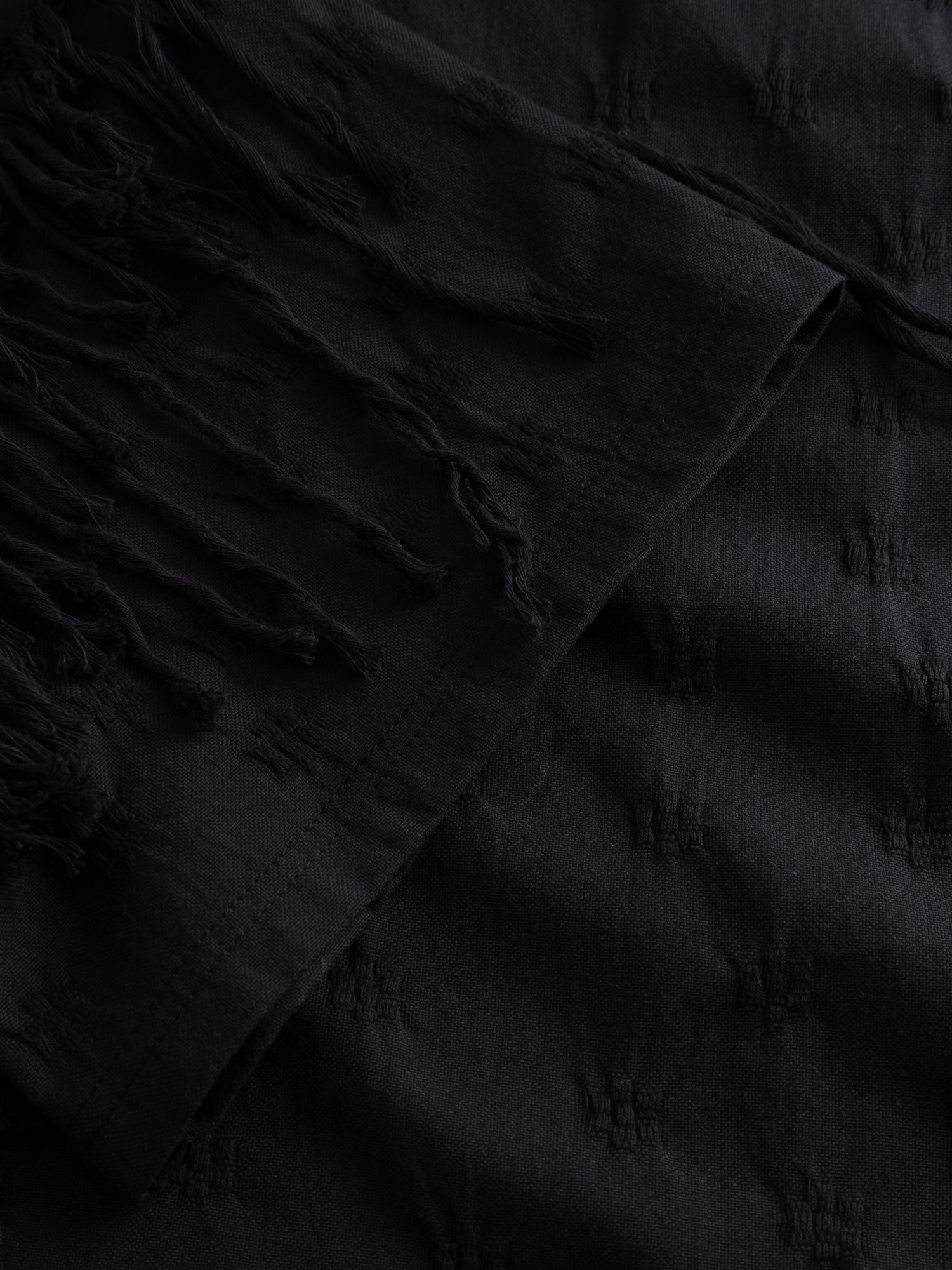 Stem Flower Tee in black, close-up of fringe detailing along seam edge and adjustable hand-pull gathering