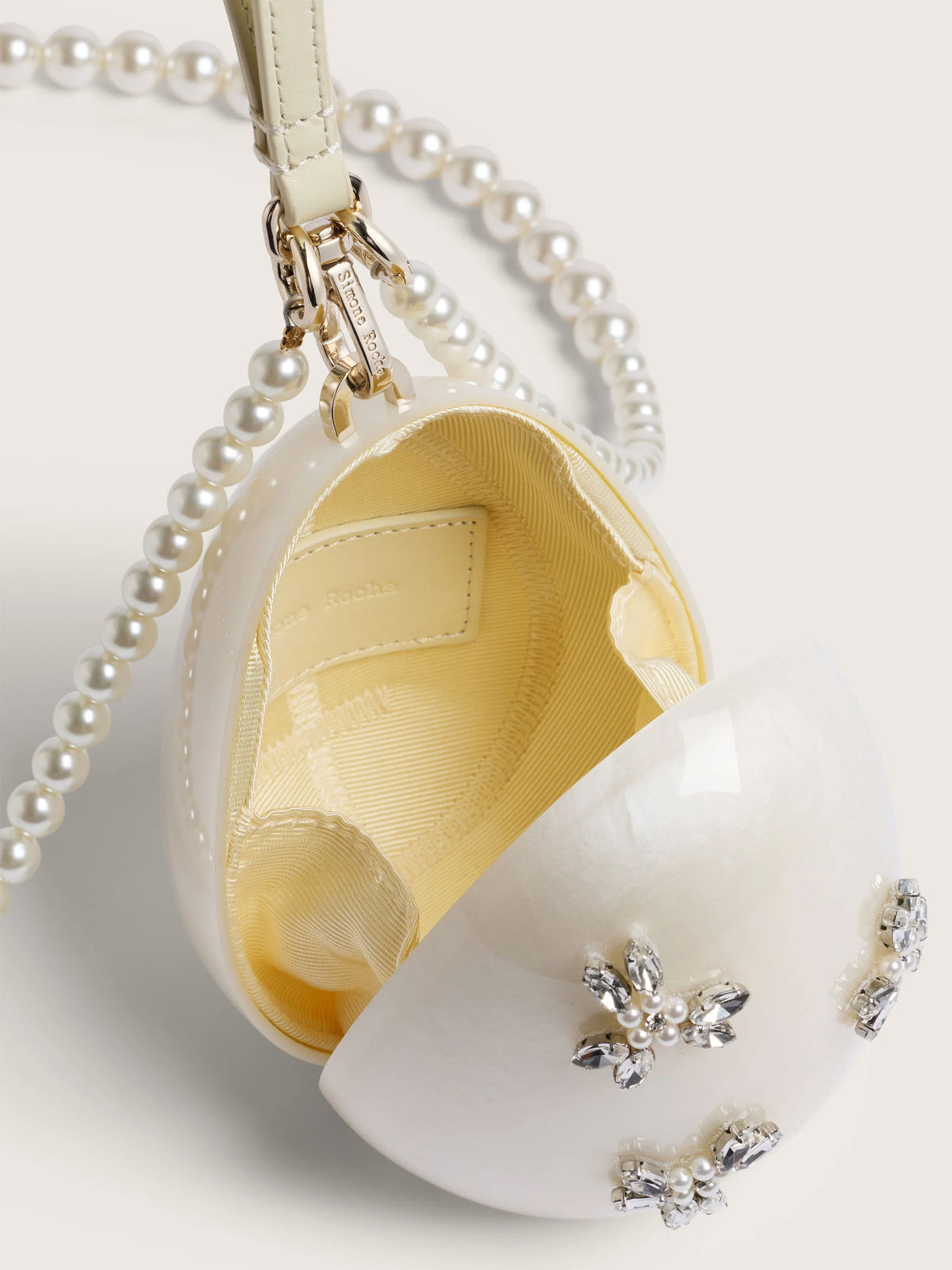 Close-up of Simone Rocha Pearl Crossbody Micro Egg Bag showing the magnetic opening, interior lining, pearl strap and crystal embellishments.