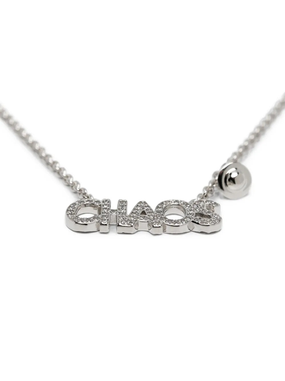 Vivienne Westwood Chaos Pendant in Platinum, close-up view of the CHAOS lettering pendant with crystal embellishment and small orb charm