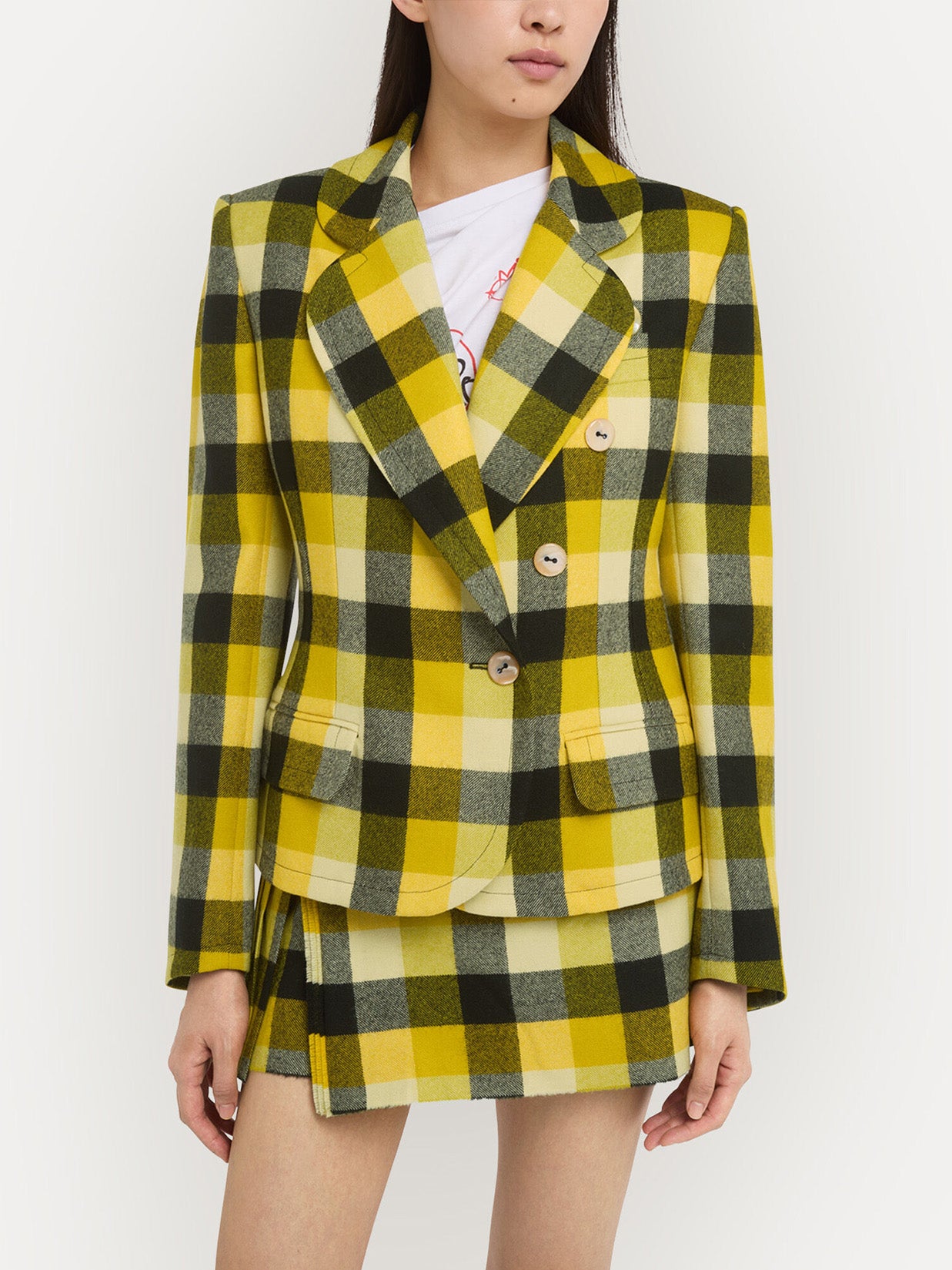 Person wearing a black and yellow checkered outfit from Vivienne Westwood on a light background.