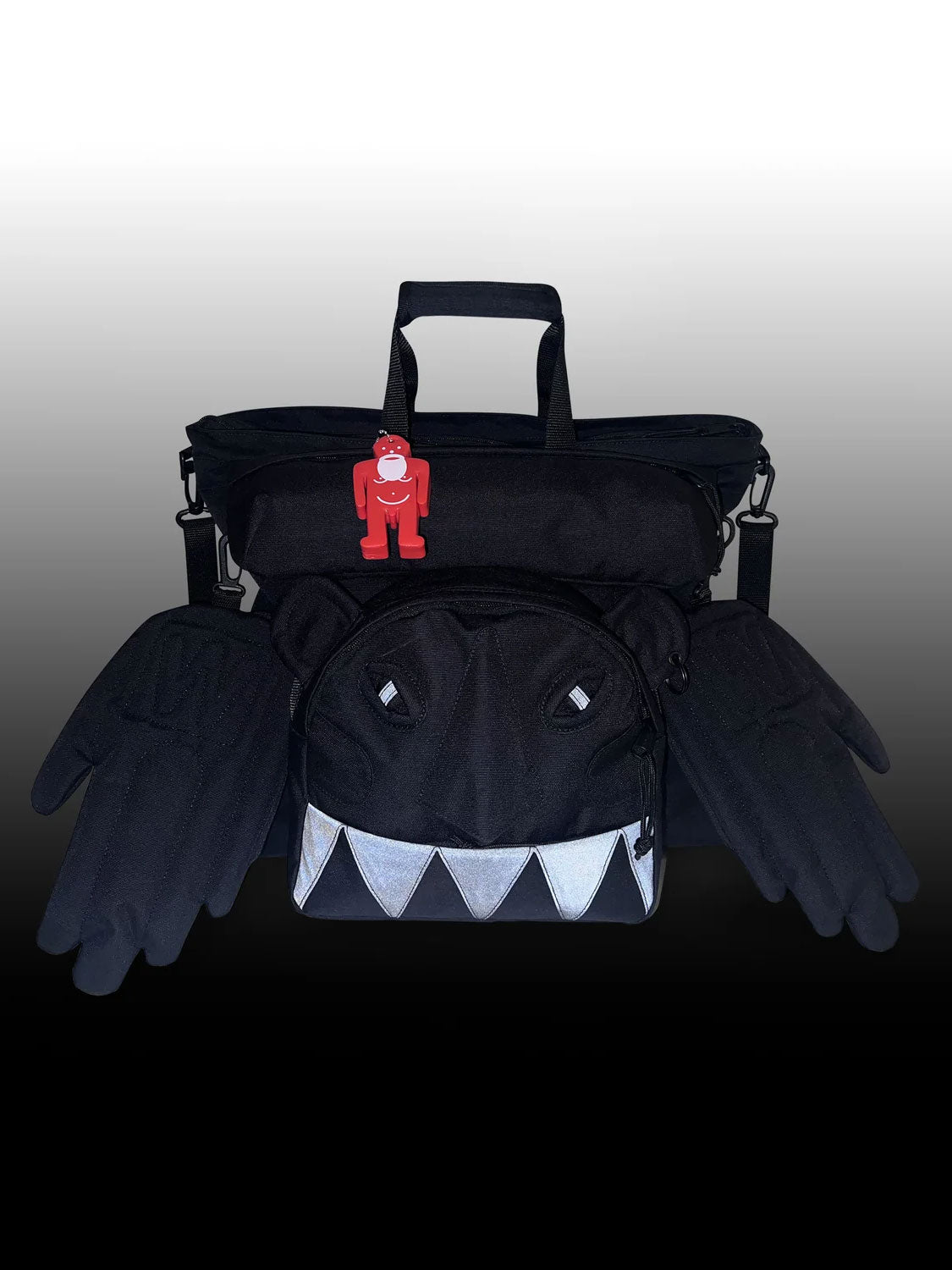 Walter Van Beirendonck x Eastpak Walter Carry Bag in Black photographed in low light, showing reflective Monster eyes and teeth