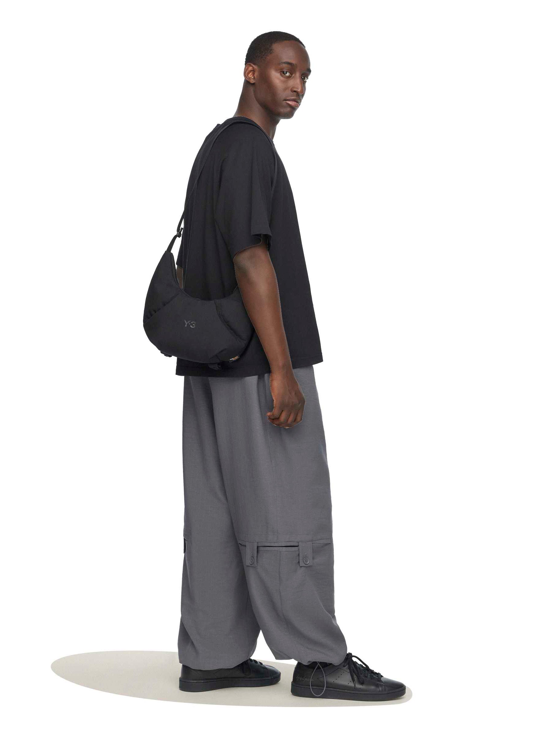 Y-3 Crescent Bag worn by model, full-length on-figure view, hand carry style, black crescent bag against grey wide-leg trousers and black tee